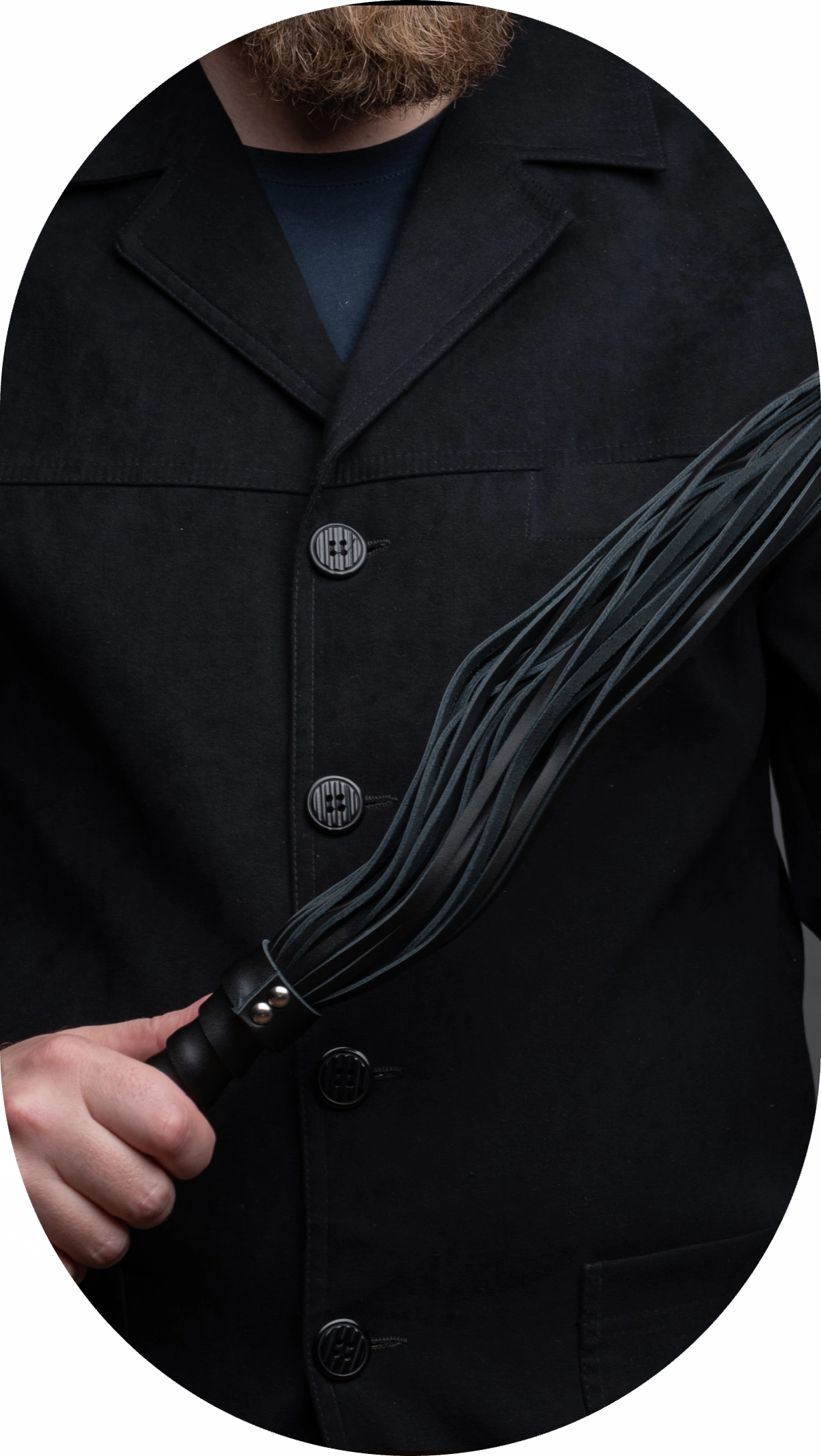 Person in black suit holding a black multi-tailed whip.