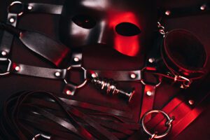 Black mask and leather restraints on display.