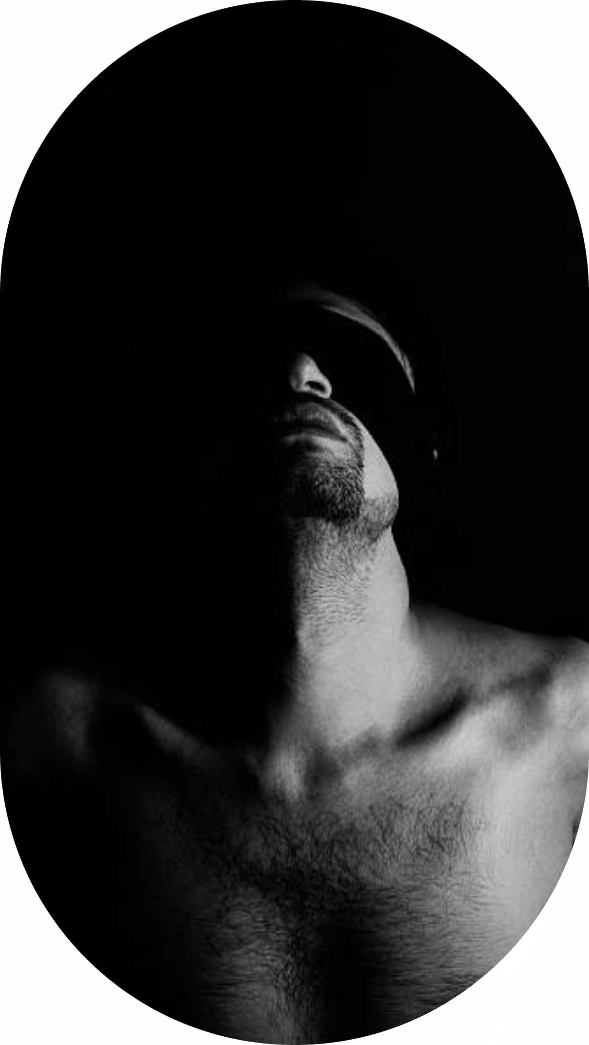 A dramatic black and white portrait highlighting half of a man's face and upper body in shadow.