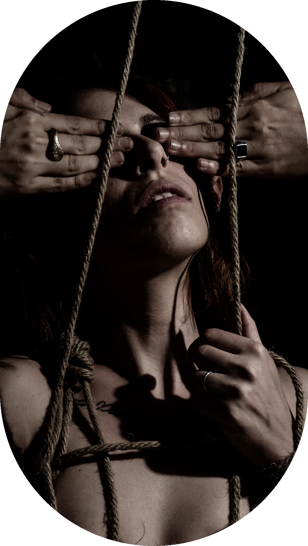 A person holding onto ropes, face partially visible in dim light.